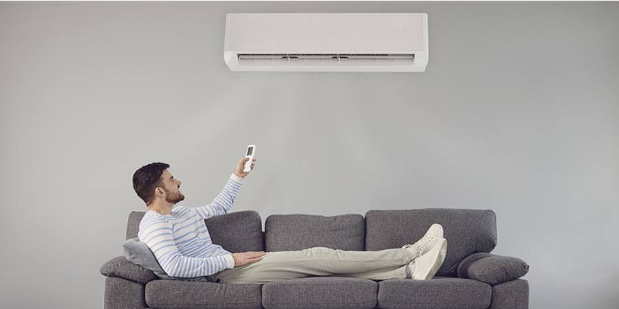 Guy lying on the couch turning on ductless ac 